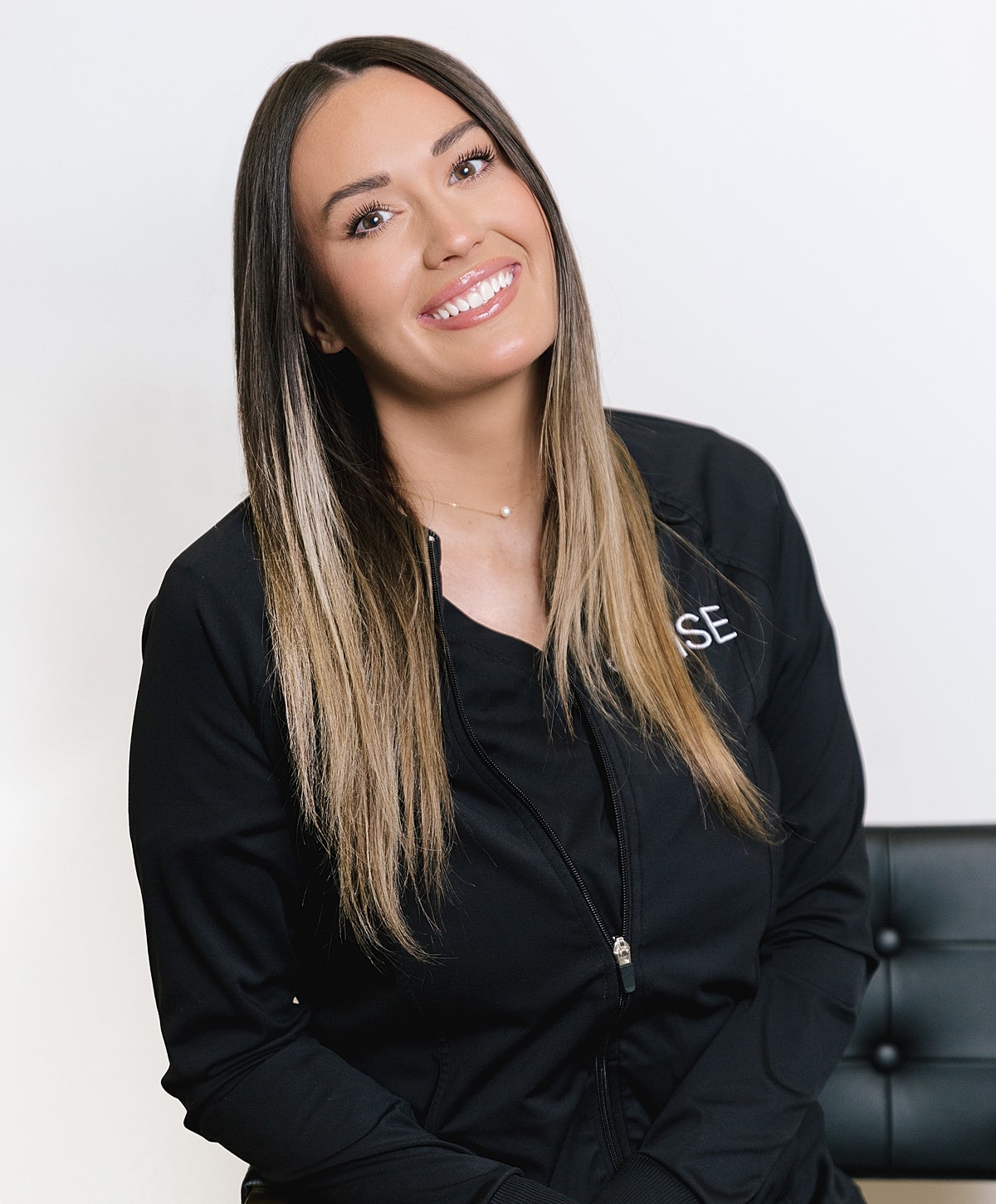 Smiling woman in professional attire, indoor setting.