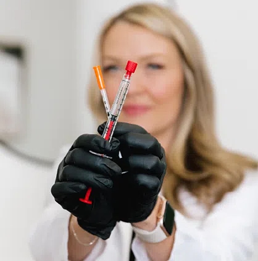 Lab technician holding syringes in gloves.