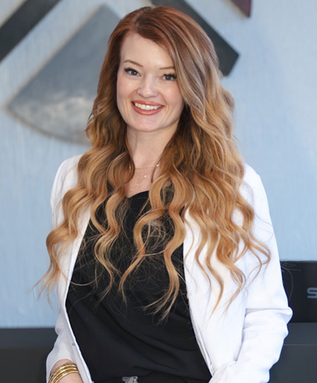 Woman with long hair smiling in professional attire.