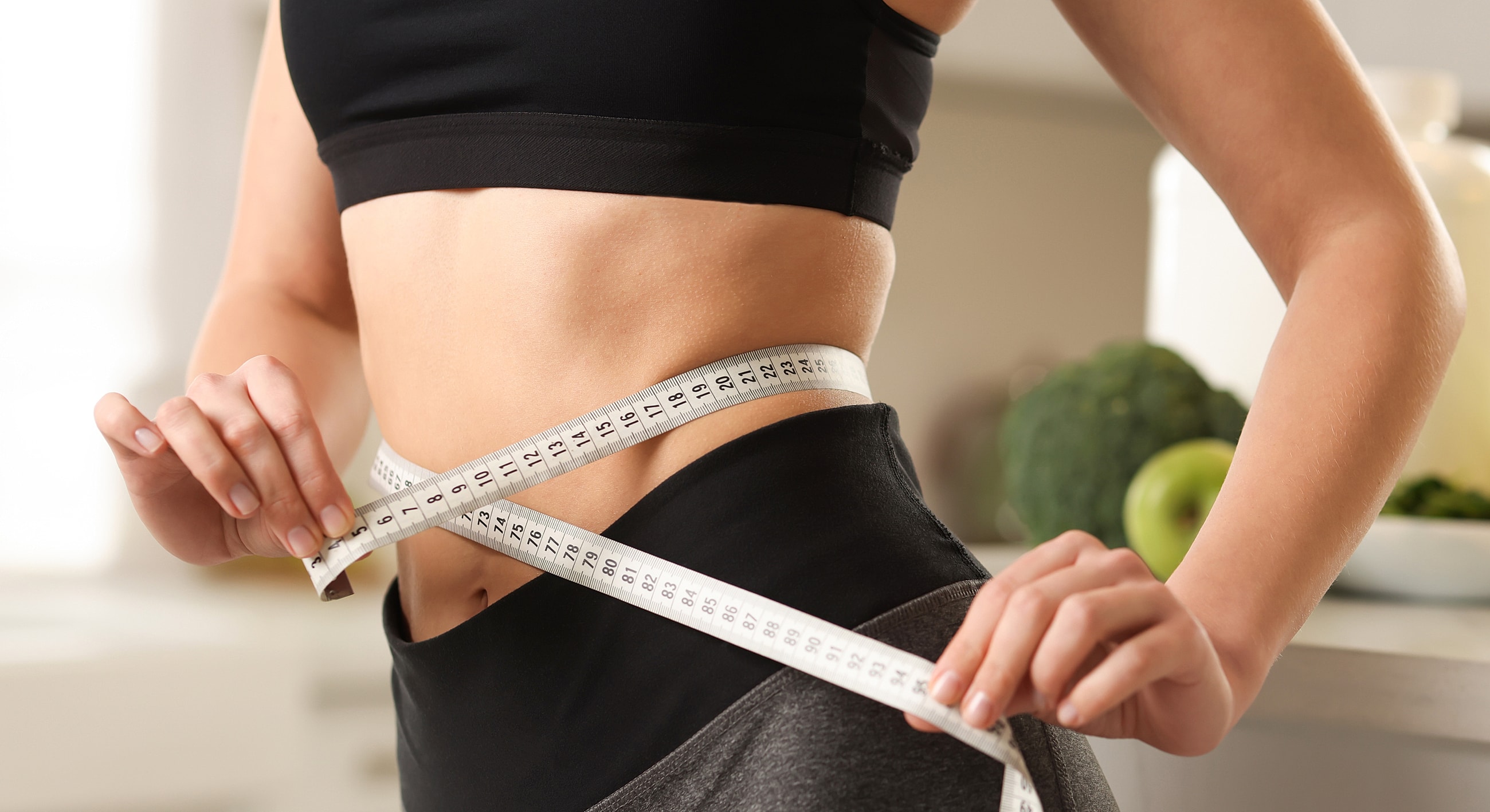 Measuring waist with tape in kitchen setting
